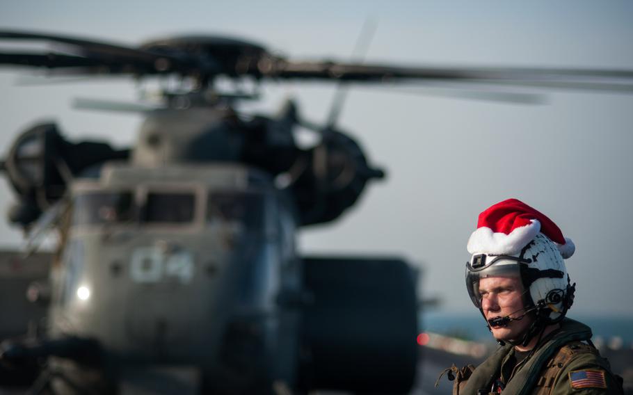 Naval Aircrewman 3rd Class Tyler Abbott, assigned to the Black Hawks of Helicopter Mine Countermeasures Squadron  15, waits while mail is unloaded from an MH-53E Sea Dragon helicopter on the flight deck of the aircraft carrier USS Harry S. Truman Dec. 19, 2013 while underway in the Persian Gulf. 
