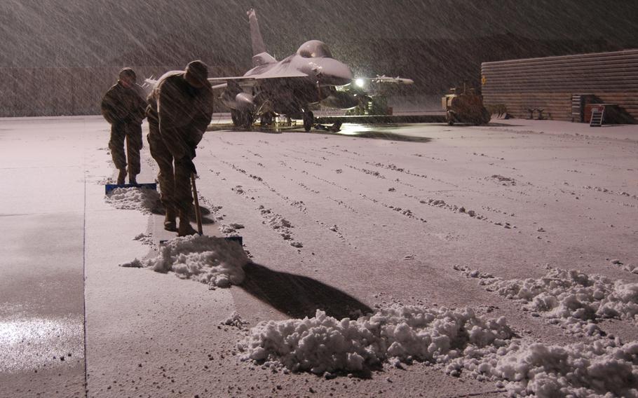 Airmen clear snow near a F-16 Fighting Falcon during a snowstorm, Sunday, Dec. 29, 2013, at Bagram Air Field, Afghanistan. Total snow accumulation was approximately three inches.