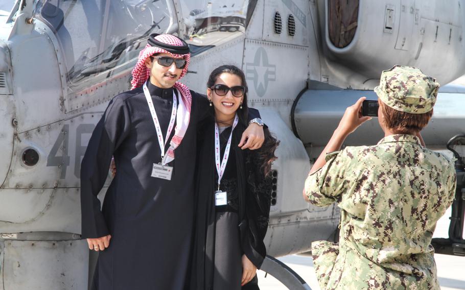A U.S. sailor takes a photo of an Arab couple posing in front of a AH-1Z Viper helicopter on display at the Bahrain International Airshow  Jan. 16, 2014. The AH-1Z Viper helicopter is one of several U.S military aircraft on display.