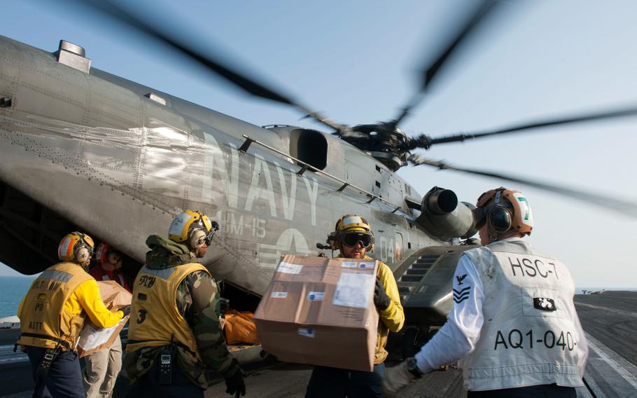 Sailors unload mail from an MH-53E Sea Dragon helicopter, assigned to the Blackhawks of Helicopter Mine Countermeasures Squadron 15, on the flight deck of the aircraft carrier USS Harry S. Truman on Dec 19, 2013 while at sea in the U.S. 5th Fleet area of responsibility.