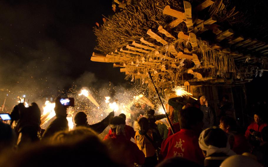 Participants in the Dosojin Fire Festival attack a tower, known as the shaden, with torches as a group of 25-year-old men defend it with pine branches.
