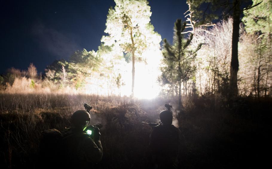 Airmen from the 1st, 2nd and 3rd Combat Camera Squadrons come under attack as explosions illuminate the forest around them during the Ability to Survive and Operate exercise on Jan. 14, 2014, at North Auxiliary Airfield, S.C.