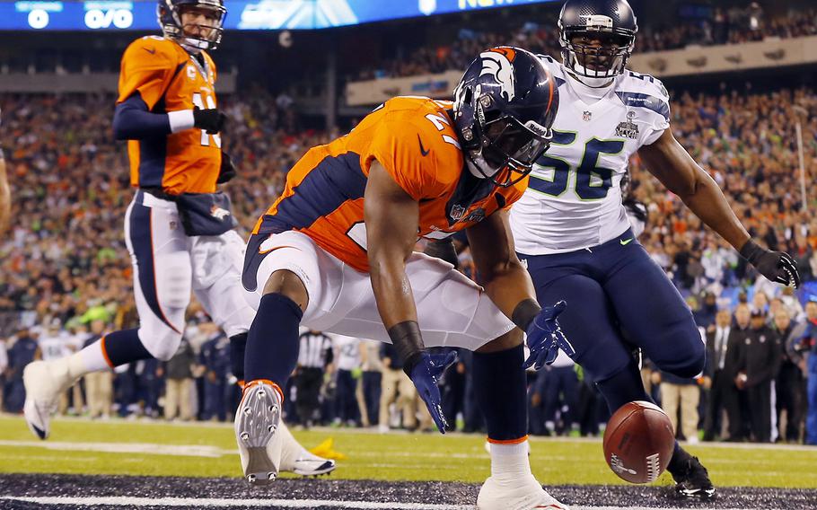 Denver Broncos' Knowshon Moreno reaches for a loose ball after the snap passed teammate Peyton Manning, left, during the first half of the NFL Super Bowl XLVIII football game Sunday, Feb. 2, 2014, in East Rutherford, N.J. Seattle Seahawks' Cliff Avril approached at right. (AP Photo/Paul Sancya)
