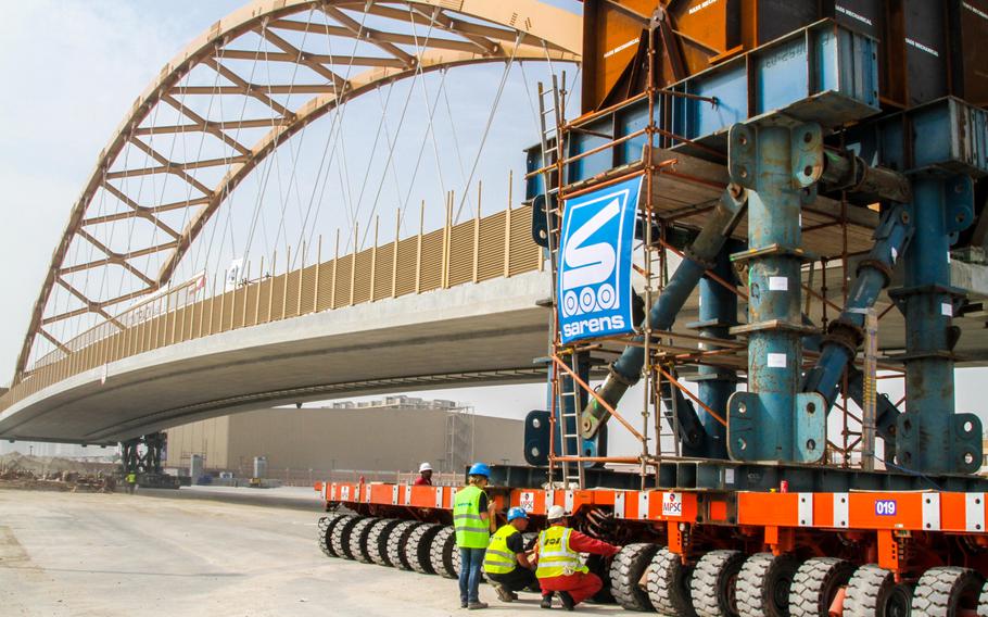 Technicians inspect the self-propelled modular trailers used to move a 400-foot long tied-arch suspension flyover bridge Jan. 30, 2014, at the U.S. Navy port facility in Bahrain.