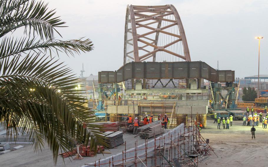 As dawn broke on Jan. 31, 2014, workers were close to finishing the move of an approximately 400-foot long tied-arch suspension flyover bridge. Overnight, the bridge was moved roughly 260 yards from the site where it was built to its permanent location where it will connect Naval Support Activity Bahrain to the U.S. Navy port facility.