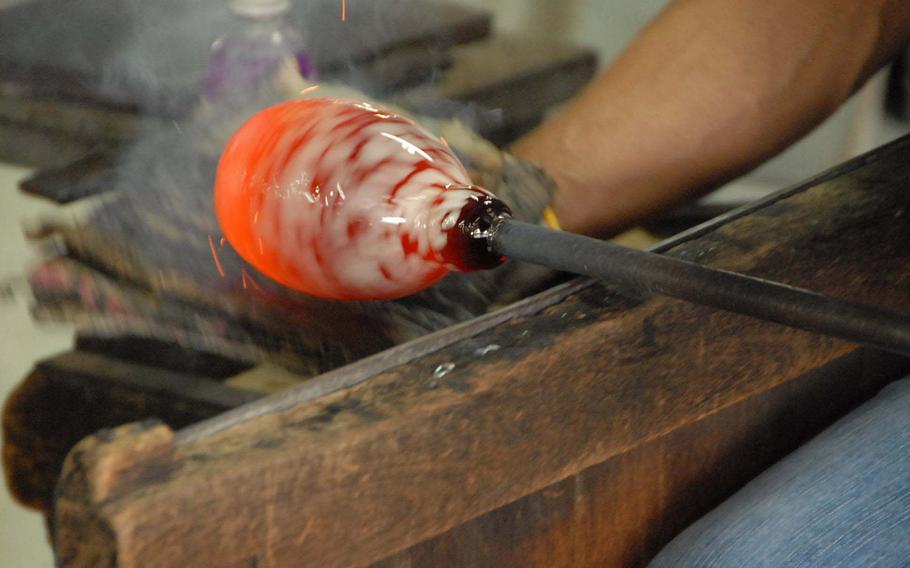 Sparks fly as a piece of molten glass is spun into shape by a Ryukyu Glass Craft worker.