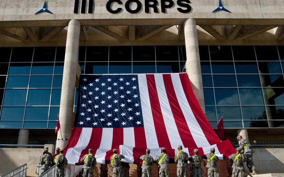 U.S. Army soldiers with the 1st Cavalry Division hang an American flag from the III Corps headquarters building on Fort Hood, Texas, on April 7, 2014, in preparation for a memorial service honoring the victims of the April 2 shooting on the base.