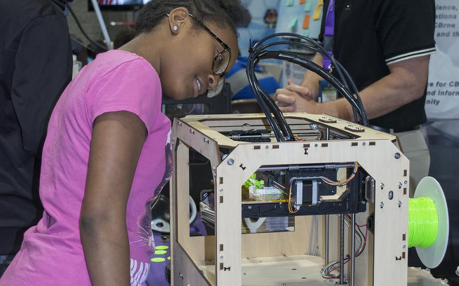 A young girl is memorized by the moving parts of the 3-D printer at the USA Science and Engineering Festival on April 25, 2014 in Washington, D.C.