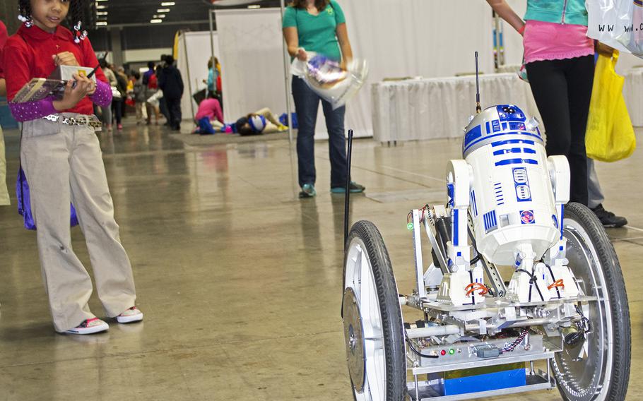 A young girl, far left, drives a robot with the Star Wars droid R2-D2 on it during the USA Science and Engineering Festival on April 25, 2014 in Washington, D.C.