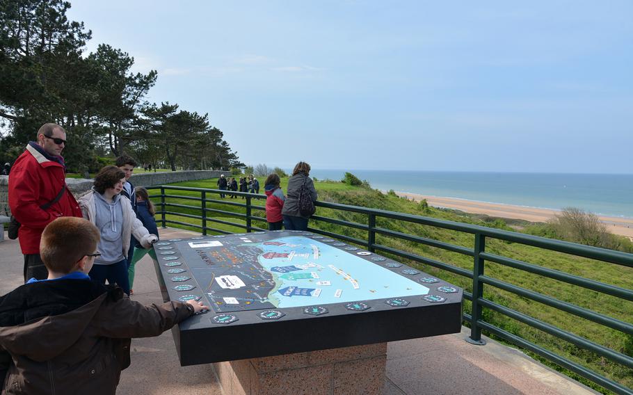 Visitors to Normandy American Cemetery study an orientation table showing all of the invasion beaches. The table overlooks the English Channel and Omaha Beach.