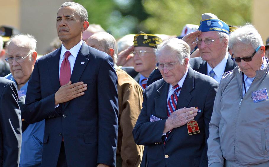 President Barack Obama and World War II veterans listen to taps at the conclusion of the ceremony at Normandy American Cemetery in Colleville-sur-Mer, on June 6, 2014, marking the 70th anniversary of D-Day.