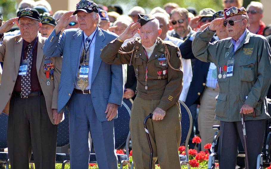World War II veterans salute during the playing of the national anthem at the ceremony at Normandy American Cemetery in Colleville-sur-Mer, on  June 6, 2014, marking the 70th anniversary of D-Day.