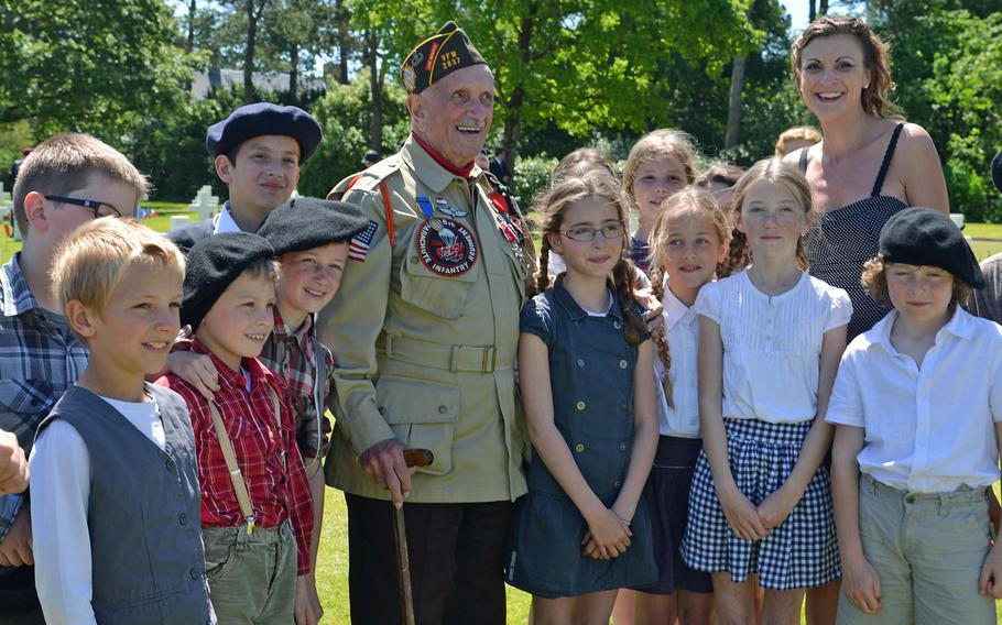 D-Day veteran Jack Schlegel, who jumped on D-Day with the 82nd Airborne's 508th Parachute Infantry Regiment poses with French children following the ceremony at Normandy American Cemetery in Colleville-sur-Mer, on June 6, 2014, marking the 70th anniversary of D-Day.