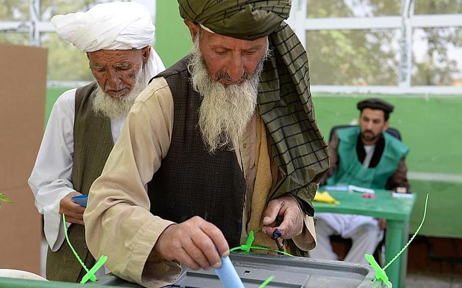 Two Afghan men cast their votes at a polling station in Wardak province, Afghanistan. A slow trickle of voters braved the polls even as at least a dozen rockets or mortar rounds exploded nearby.
