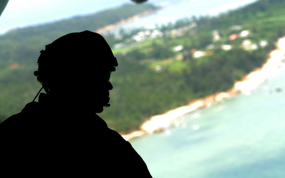 A crew chief with Marine Heavy Helicopter Squadron 361 looks out over Okinawa from a CH-53 Super Stallion before fast-rope training in northern Okinawa, June 17, 2014.