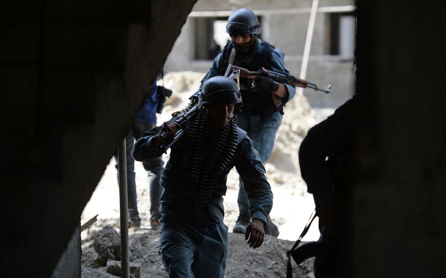 Afghan policemen take up positions in a building during a firefight with Taliban insurgents on Thursday, July 17, 2014. The attackers were firing on the Kabul airport before being killed by security forces.