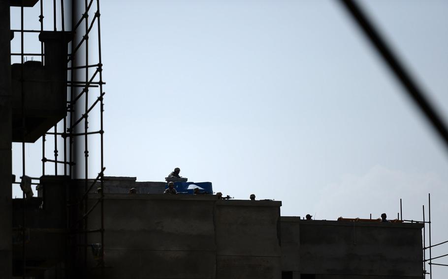 Afghan security forces fire from the top of a partially constructed building during a firefight with Taliban militants on July 17, 2014. The four insurgents face off against hundreds of Afghan government forces in a construction area next to the Kabul airport.