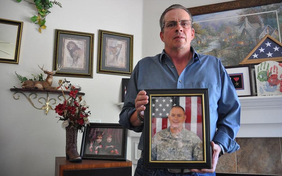 Jerry Brown holds a photo of his son, Staff Sgt. Daniel Brown, who was killed by a roadside bomb in Afghanistan on March 24, 2012. At left, a photo shows Dan's twin daughters, born three months before his death, and whom he never met.