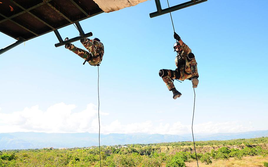 Members of the an Uruguay special operations team start their descent down a rappel tower during the first part of the Fuerzas Comando stress test event at Fort Tolamaida, Colombia, July 28, 2014. The stress events are designed to see how steady a competitor?s aim is after he?s been pushed to the point of physical exhaustion.