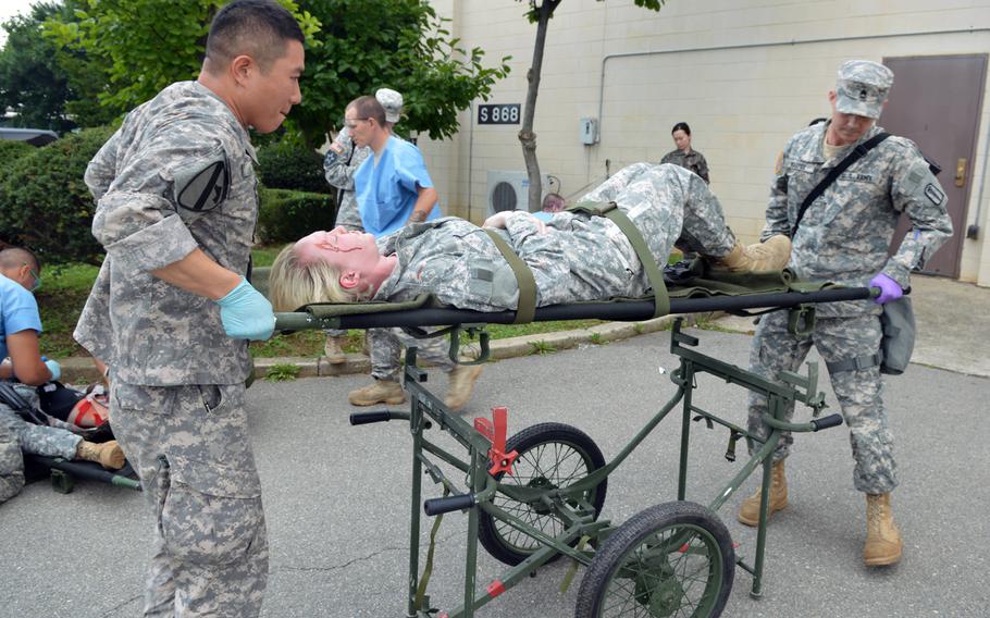 Soldiers with the 121st Combat Support place a soldier with simulated injuries on a gurney at Camp Humphreys, South Korea on Aug. 22, 2014. More than 30,000 troops are participating in the Ulchi Freedom Guardian exercise this month.