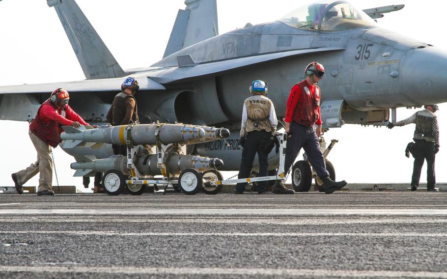 Aviation ordnance members move ordinance across the flight deck of the USS George H.W. Bush, on Aug. 10, 2014, which it was underway in the Persian Gulf.
