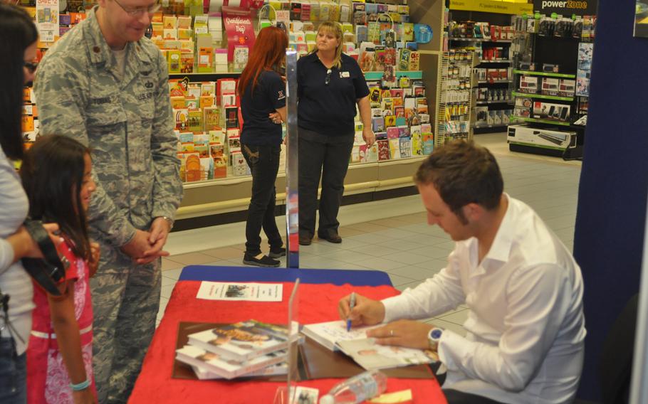 Luca Manfé signs books for Maj. Adam Tobias, his wife, Laura, and daughter Mia at a Aviano Air Base exchange on Sept. 3.