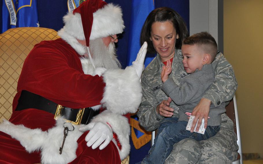 Santa Claus high-fives a servicemember's child during his visit to the Air Reserve Personnel Center Dec. 19, 2014, on Buckley Air Force Base, Colo.