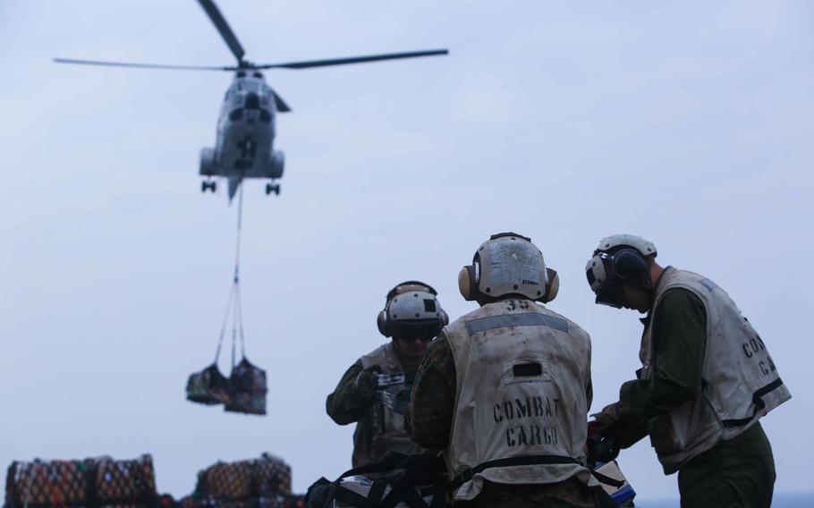 U.S. Marines from the 11th Marine Expeditionary Unit, assigned to the combat cargo division of the amphibious assault ship USS Makin Island, secure a pallet during an underway replenishment aboard the Makin Island, Jan. 6, 2014.