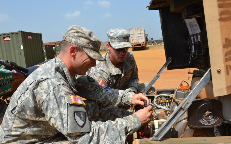 Sgt. Austin Lumpkin, left, and Cpl. James Lenke, both of Headquarters and Headquarters Company, 62nd Engineer Battalion, 36th Engineer Brigade, perform checks on a generator at the emergency control point, Dec. 26, 2014, at the National Police Training Academy, Paynesville, Liberia, in support of Operation United Assistance.