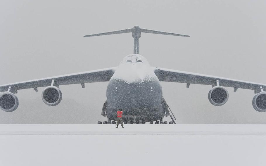 An aircraft maintainer stands on the flightline in front of a snow-covered C-5M Super Galaxy on Tuesday, Jan. 6, 2015, at Dover Air Force Base, Del. Aircraft maintenance operations continued despite 1.4 inches of snow.