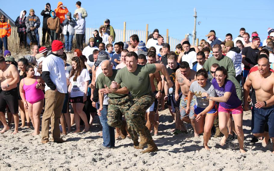 Col. Matthew G. St. Clair, center left, commanding officer, Ground Combat Element Integrated Task Force, and 1st. Lt. Philip J. Kulczewski, center right, public affairs officer, Headquarters and Service Company, GCEITF, rush to the water during the Special Olympics Onslow County Polar Plunge at Onslow Beach at Marine Corps Base Camp Lejeune, N.C., Jan. 10, 2015.