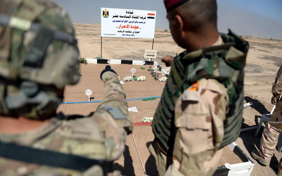 A U.S. soldier, left, and an Iraqi officer use a diorama to plan an exercise for Iraqi troops at the Besmaya training center south of Baghdad.