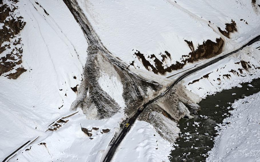 Cars make their way along a road cleared from the debris of an avalanche in Panjshir valley in central Afghanistan on Saturday, Feb. 28, 2015. Dozens of such avalanches buried roads and communities, killing as many as 200 people.