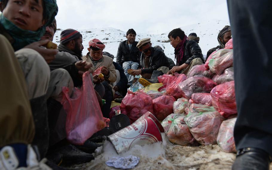 Men take a lunch break Saturday, Feb. 28, 2015, in the back of a dump truck loaded with emergency meals for villagers stranded in Afghanistan's high mountain valleys by heavy snow and avalanches.