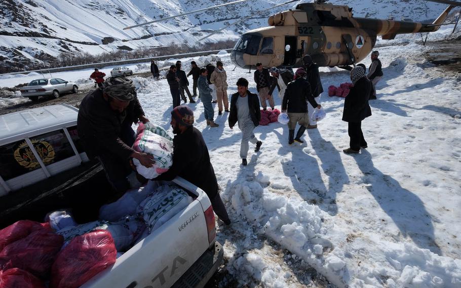 Men load an Afghan Air Force Mi-17 on Saturday, Feb. 28, 2015, with emergency meals to be delivered to communities cut off after avalanches killed some 200 people and buried roads in several provinces. Security forces flew daily missions to resupply villages and help evacuate sick and injured people.