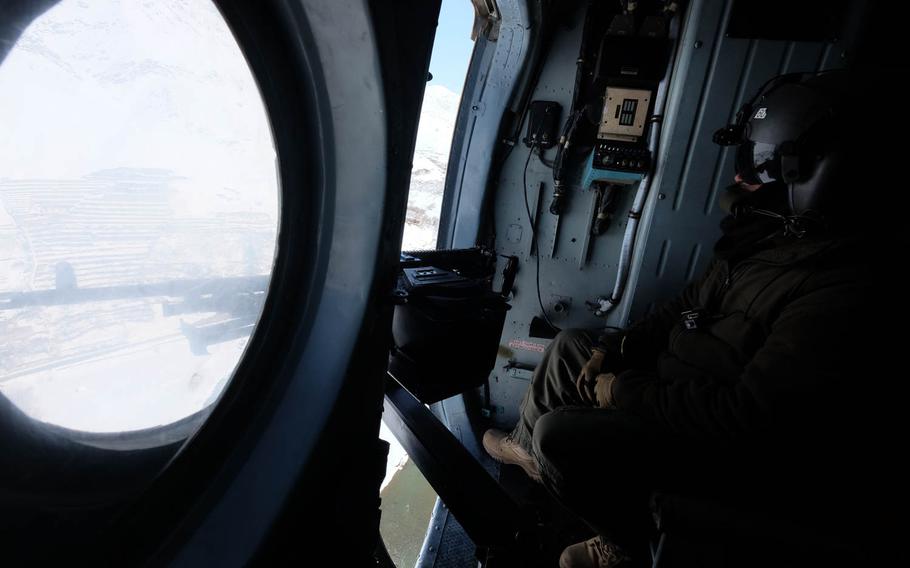 An Afghan Air Force crew chief looks out the window of an Mi-17 helicopter as it flies an emergency mission on Saturday, Feb. 28, 2015, to drop supplies to villages and police outposts stranded in snow. At least three Afghan Air Force helicopters flew from a makeshift staging ground in Panjshir valley to bring supplies and evacuate wounded.