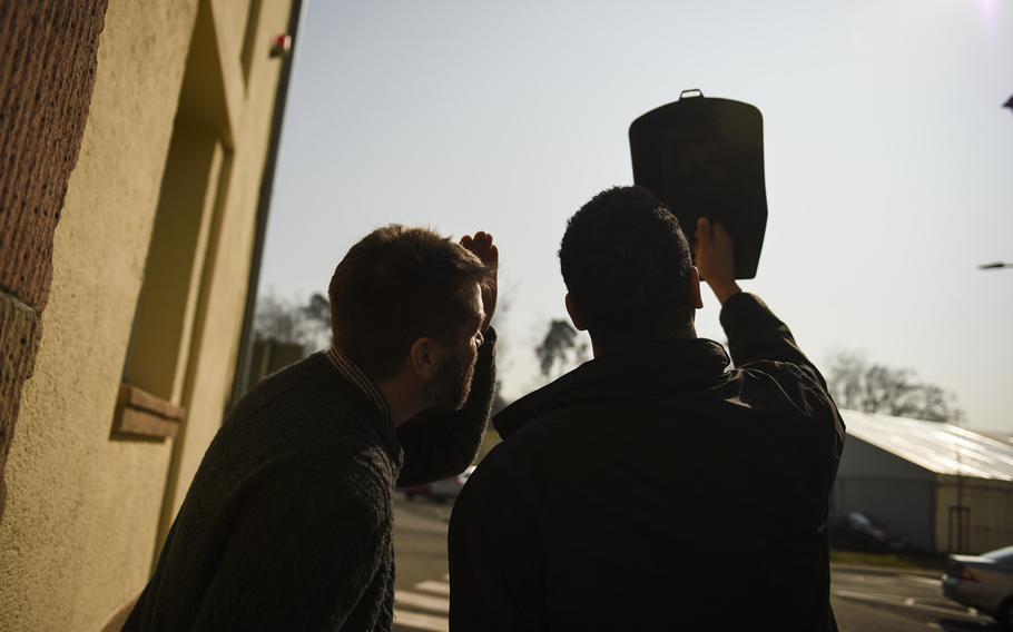 Stars and Stripes employees Shane Schiermeier and James Jones look at the partial solar eclipse through a welding mask Friday, March 20, 2015 on Kleber Kaserne, in Kaiserslautern, Germany.