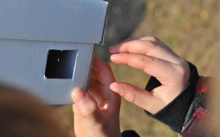 The sun's image appears as a tiny crescent moon inside the viewing hole of a cardboard pinhole projector. Yvonne Engels' second-grade class at Ramstein Elementary School spent the morning of March 20, 2015, exploring nature and viewing the partial solar eclipse over northern Europe through handmade pinhole projectors at the base pond on Ramstein Air Base, Germany.