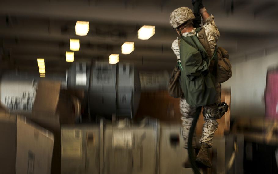 A U.S. Marine with Company L, Battalion Landing Team 3rd Battalion, 1st Marine Regiment, 15th Marine Expeditionary Unit, fast ropes in the hangar bay of the USS Essex during Composite Training Unit Exercise off the coast of San Diego on March 23, 2015.