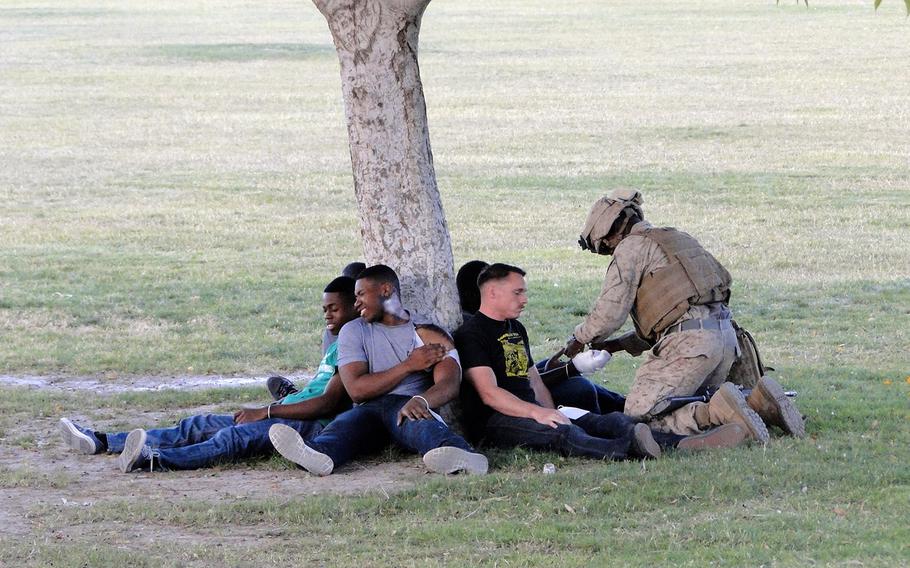 A Marine tends to role players acting as injured civilians during a simulated humanitarian aid mission Friday in Yuma, Ariz. The exercise, which also included a simulated embassy evacuation, was part of Weapons and Tactics Instructor course.