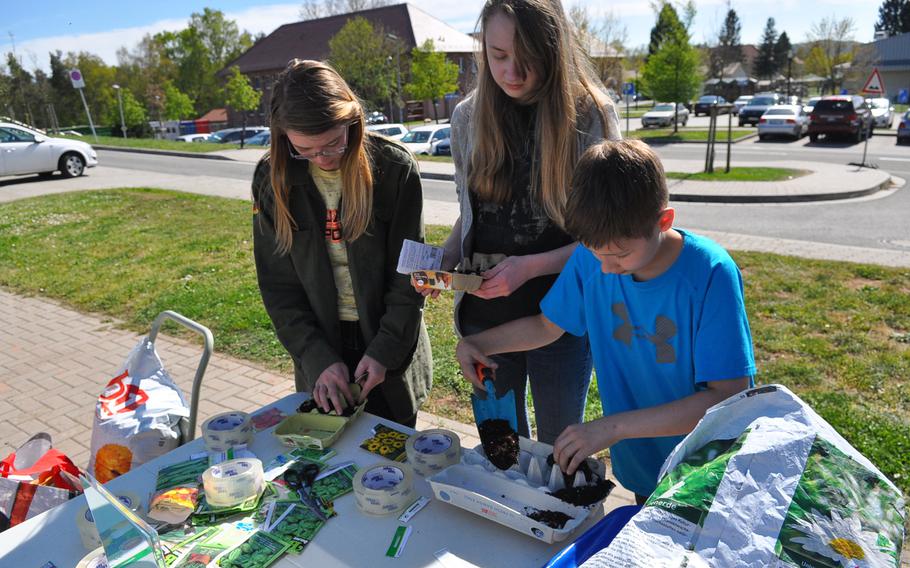 Julia Wemhoff, left, Jasmine Rebik, center, and Bryce Wehmeyer plant an "egg-carton garden" on April 22, 2015, outside the U.S. Army Garrison Rheinland-Pfalz Main Library at Landstuhl, Germany. For Earth Day, the library provided patrons with a variety of flower and vegetable seeds that they could plant in an egg carton to take home and grow a garden.