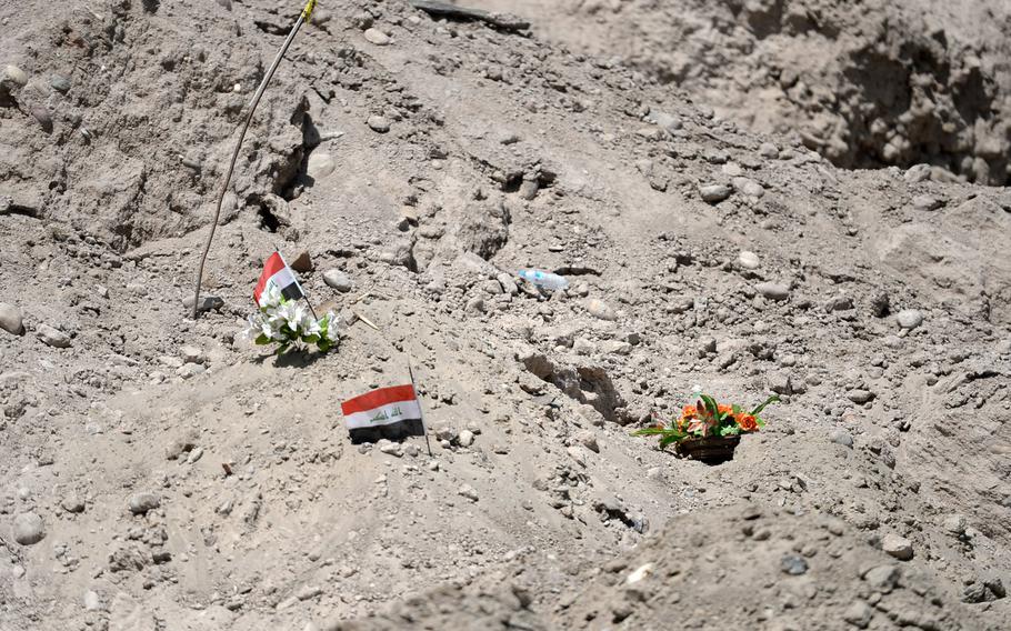 Flags and flowers mark the location of one of 13 mass graves found around Tikrit, Iraq. Islamic State militants massacred an estimated 1,700 people before burying or throwing their bodies in a river.