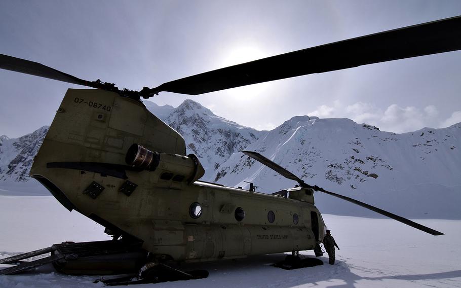 An aviator from the 1st Battalion, 52nd Aviation Regiment stands outside a CH-47F Chinook helicopter at the Kahiltna Glacier base camp on Mount McKinley in the shadow of 13,965-foot Mount Hunter on April 27, 2015.
