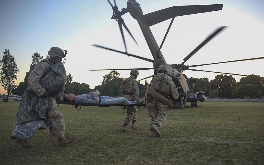 Marines and sailors with 1st Battalion, 5th Marine Regiment, transport notionally-injured role-players to be medically evacuated by a CH-53E Super Stallion helicopter during a foreign humanitarian assistance exercise at Kiwanis Park, Yuma, Arizona, as part of Weapons and Tactics Instructor Course 2-15, April 17.