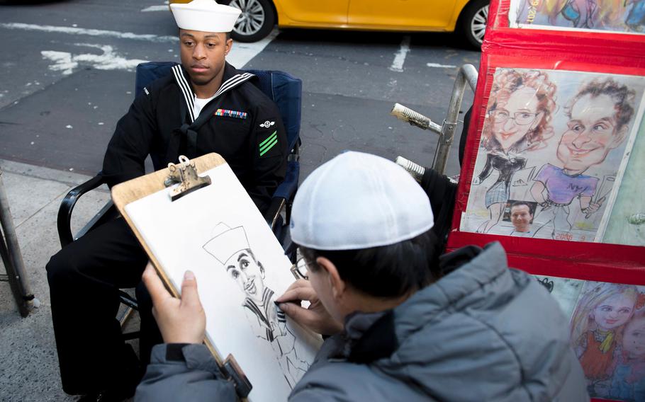 Airman Aaron Waters, a sailor stationed on USS New York, gets a caricature drawn while visiting New York City's Times Square Nov. 9, 2015.