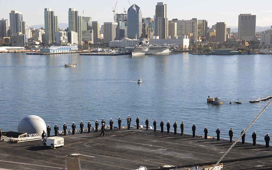 Sailors and Marines man the rails while the aircraft carrier USS Theodore Roosevelt moors to the pier at her new homeport of San Diego on Nov. 23, 2015. Theodore Roosevelt arrived in San Diego after completing an eight-month around the world deployment.