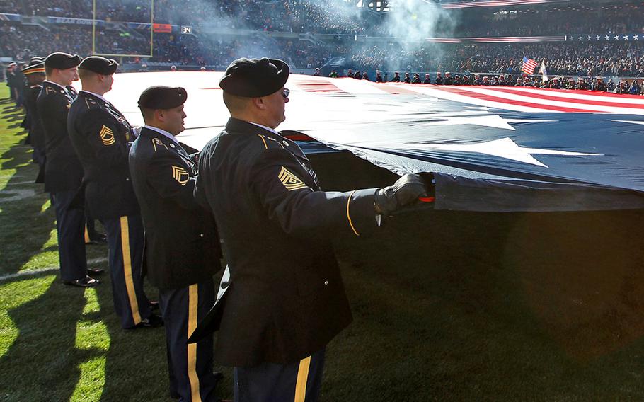 Servicemembers from each branch of service unfurl a giant American flag during the Chicago Bears Veterans Day pre-game ceremonies at Soldier Field in Chicago, Nov. 22, 2015. More than 100 servicemembers participated in the recognition honoring veterans for their service.