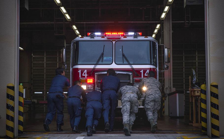 Firefighters with the 374th Civil Engineer Squadron push fire engine 14 into the main firehouse at Yokota Air Base, Japan, Nov. 25, 2015. Yokota firefighters pushed the truck by hand to conclude a blessing and dedication ceremony for the new vehicle.