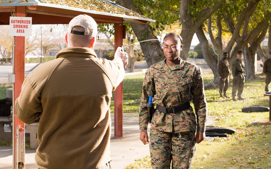 Thomas Streeter, lead instructor of Homeland Security Solutions Inc. at Marine Corps Logistics Base Barstow, Calif., sprays Sgt. Gratia Akakpo with oleoresin capsicum, or pepper spray, during the MCLB security augmentation force training Dec. 8, 2015.