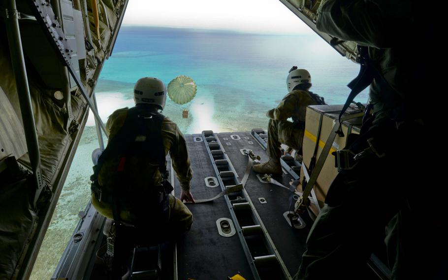 Cpl. Teome Matamua and Sgt. Phillip McIllvaney, Australian Army 176th Air Dispatch Squadron loadmasters, deliver the first low-cost, low-altitude bundle of Operation Christmas Drop 2015 to the island of MogMog, on Tuesday, Dec. 8, 2015. Australian and Japanese C-130 aircrews joined U.S. airmen during the 64th year of Operation Christmas Drop. Aircrews drop critical supplies to 56 islands throughout the Commonwealth of the Northern Marianas, Federated States of Micronesia and Republic of Palau.